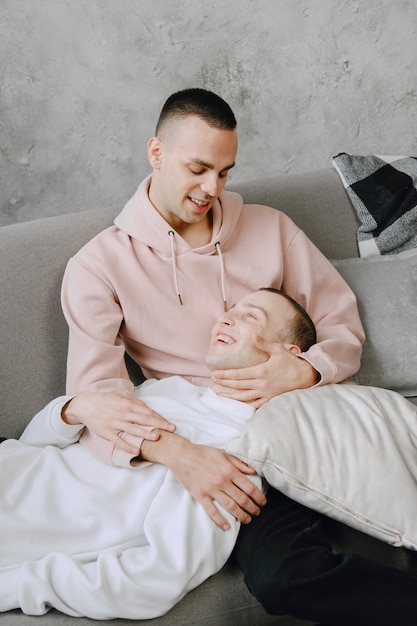 Young romantic lgbtq couple spending day cuddling and relaxing on the couch. Different family lifestyle concept.