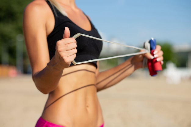 Молодая спортивная женщина бегуна делает упражнения на растяжку на пляже. Копировать пространство