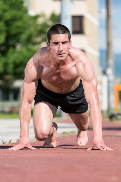 Young Runner In Starting Position On Track