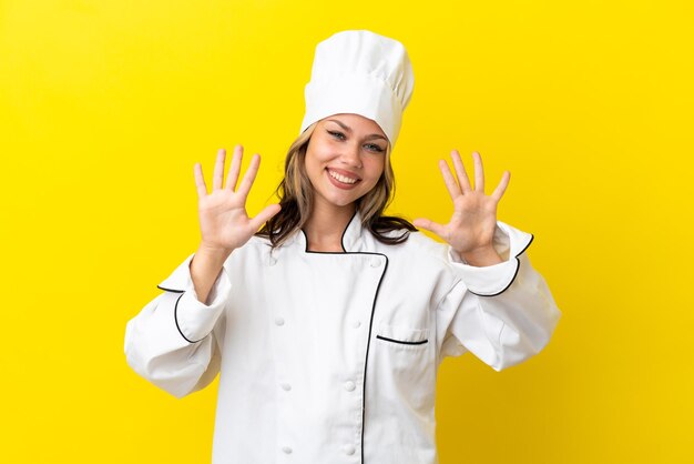 Young Russian chef girl isolated on yellow background counting ten with fingers