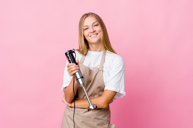 Young russian cook woman holding an electric mixer isolated who feels confident, crossing arms with determination.