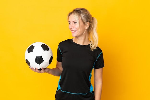 Фото Молодой российский футболист женщина изолирована на желтом фоне смотрит сторону
