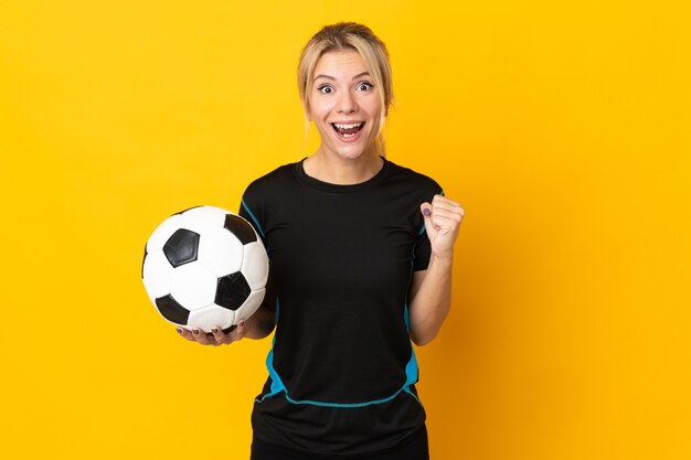 Young Russian football player woman isolated on yellow background celebrating a victory in winner position