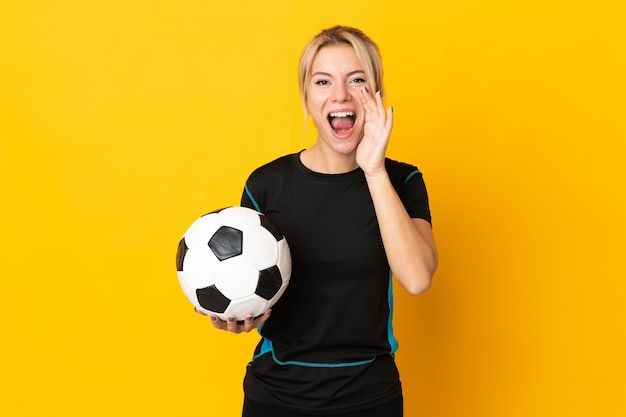 Young Russian football player woman isolated on yellow shouting with mouth wide open