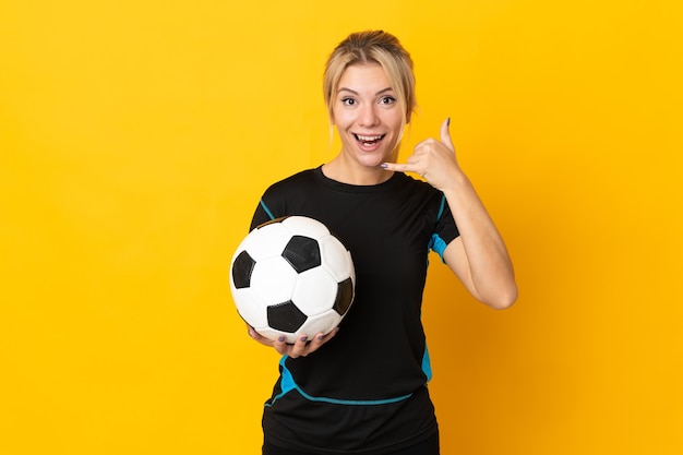 Young Russian football player woman isolated on yellow wall making phone gesture. Call me back sign