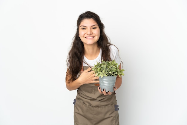 Молодая русская девушка-садовник держит изолированное растение, много улыбаясь