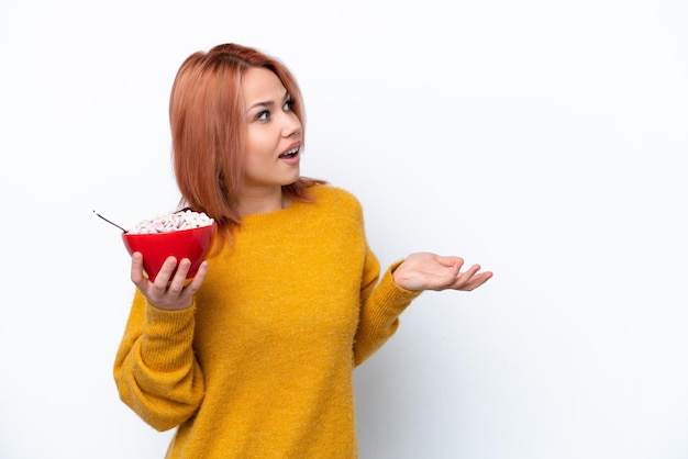 Young Russian girl holding a bowl of cereales isolated on white background with surprise facial expression