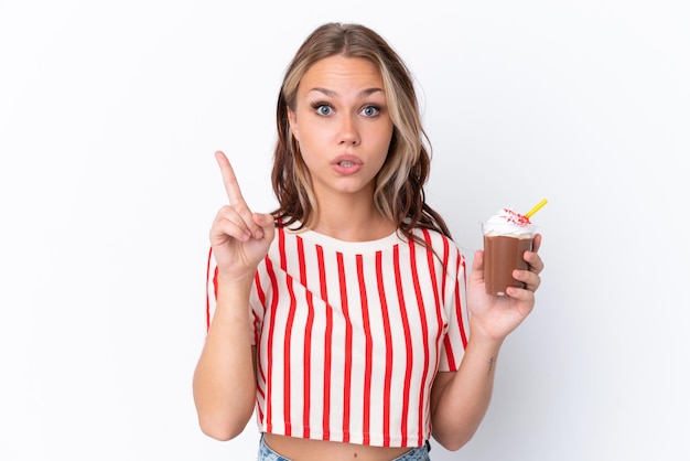 Young Russian girl holding cappuccino isolated on white background intending to realizes the solution while lifting a finger up