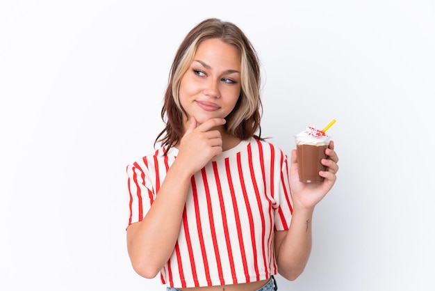 Young Russian girl holding cappuccino isolated on white background looking to the side and smiling