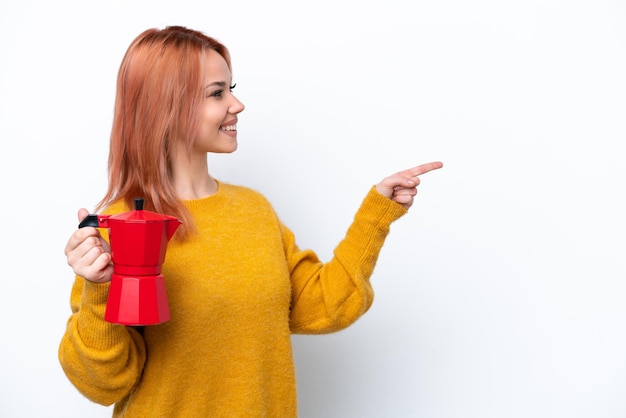 Young Russian girl holding coffee pot isolated on white background pointing to the side to present a product