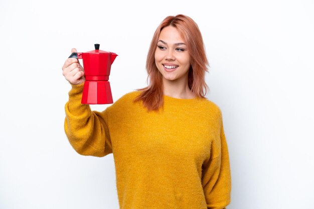 Молодая русская девушка держит кофейник на белом фоне со счастливым выражением лица