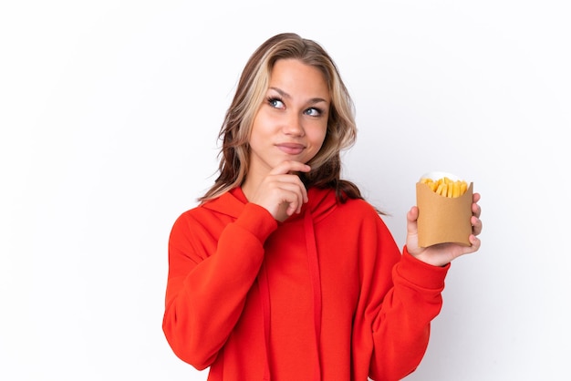 Young Russian girl holding fried chips isolated on white background and looking up