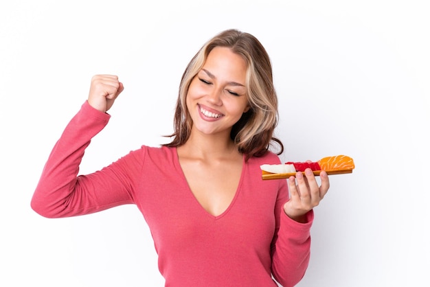 Young Russian girl holding sashimi isolated on white background celebrating a victory