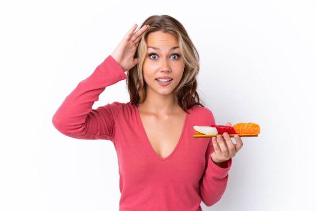 Young Russian girl holding sashimi isolated on white background with surprise expression