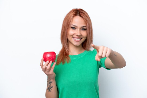 Young Russian girl with an apple isolated on white background points finger at you with a confident expression