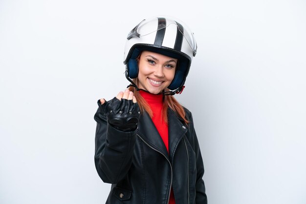 手で来るように誘う白い背景で隔離のオートバイのヘルメットを持つ若いロシアの女の子あなたが来たことを幸せに