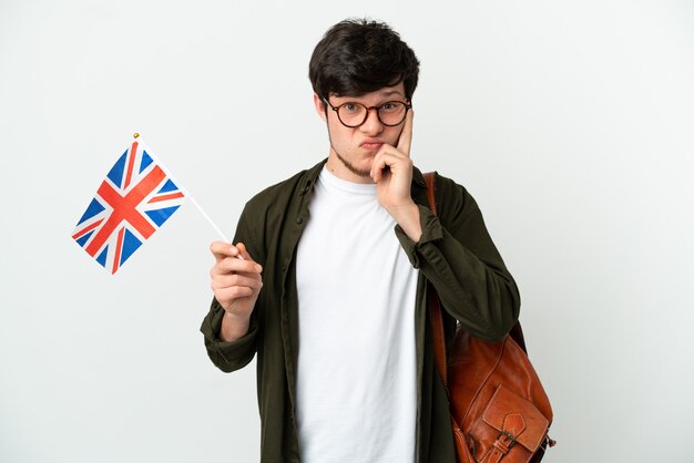 Young Russian man holding an United Kingdom flag isolated on white background thinking an idea