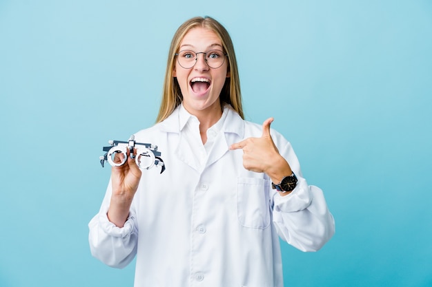 Young russian optometrist woman on blue surprised pointing with finger, smiling broadly.