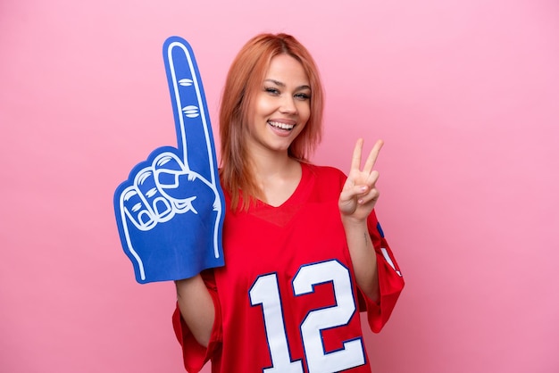 Young Russian rugby fan girl isolated on pink background smiling and showing victory sign