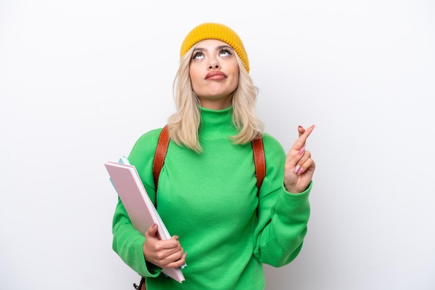 Young russian student woman isolated on white background with\
fingers crossing and wishing the best