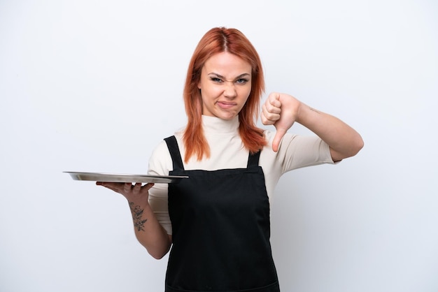 Young Russian waiter with tray isolated on white background showing thumb down with negative expression