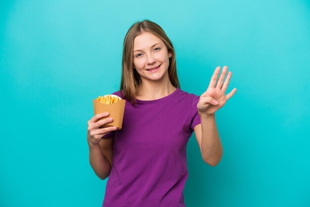 幸せな青い背景に分離されたフライドポテトをキャッチし、指で4を数える若いロシアの女性