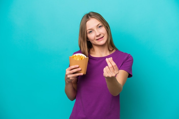 お金のジェスチャーを作る青い背景に分離されたフライドポテトをキャッチする若いロシアの女性