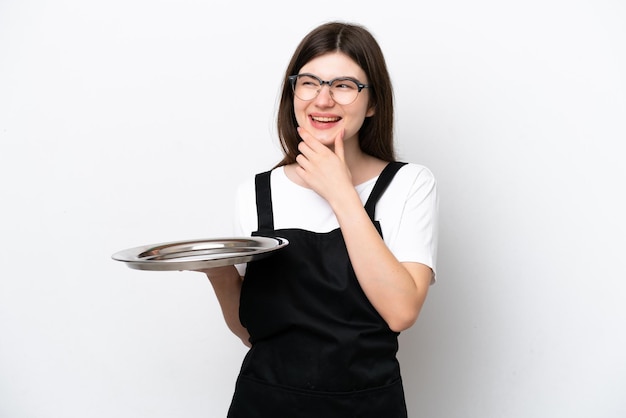 Young Russian woman chef with tray isolated on white background looking to the side and smiling