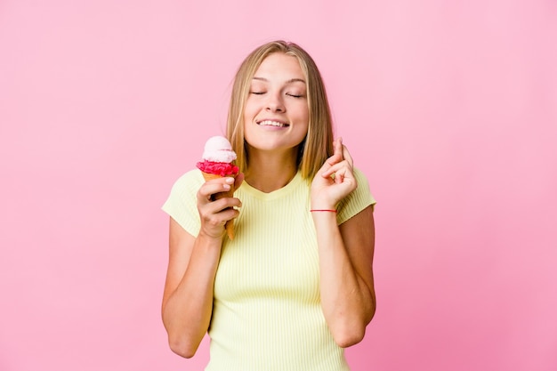 Giovane donna russa che mangia un gelato isolato alzando il pugno, sentendosi felice e di successo. concetto di vittoria.