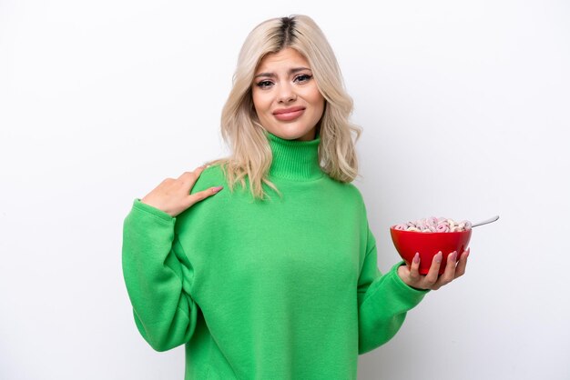 Photo young russian woman holding a bowl of cereals isolated on white background suffering from pain in shoulder for having made an effort