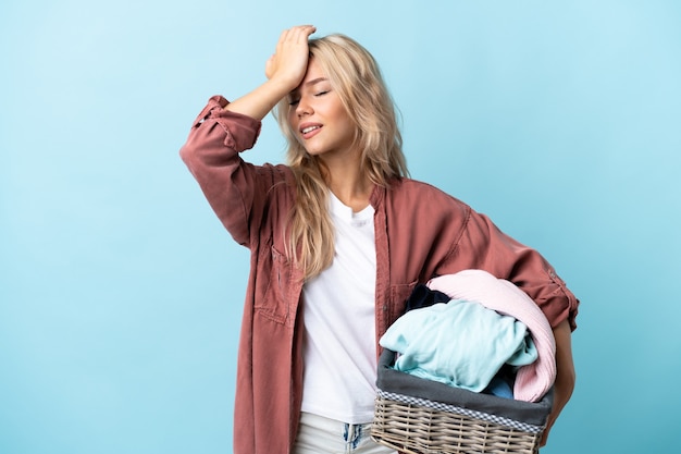 Young Russian woman holding a clothes basket isolated on blue has realized something and intending the solution