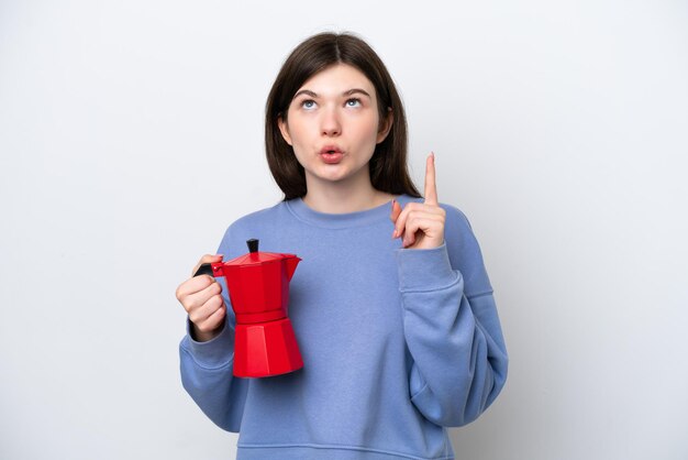 Young Russian woman holding coffee pot isolated on white background thinking an idea pointing the finger up