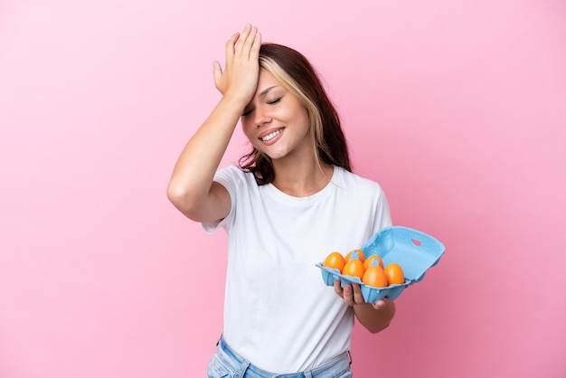 Young Russian woman holding eggs isolated on pink background has realized something and intending the solution