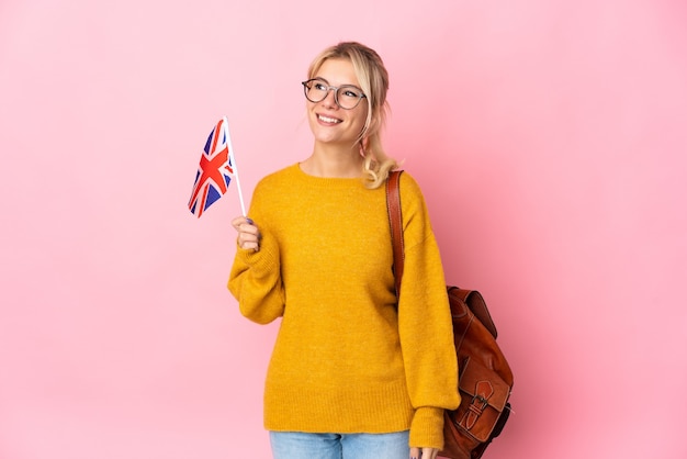 Photo young russian woman holding an united kingdom flag isolated on pink background thinking an idea while looking up