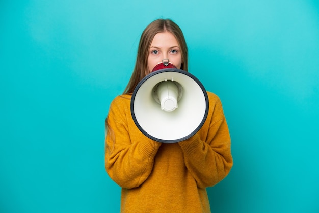 Young Russian woman isolated on blue background shouting through a megaphone to announce something