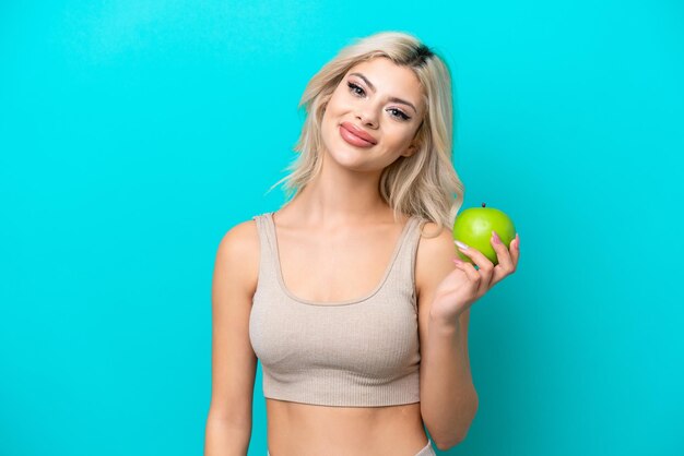 Young Russian woman isolated on blue background with an apple