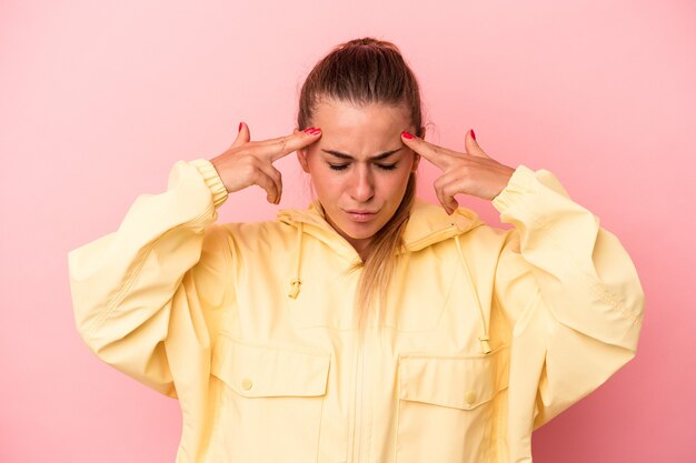 Young Russian woman isolated on pink background focused on a task, keeping forefingers pointing head.