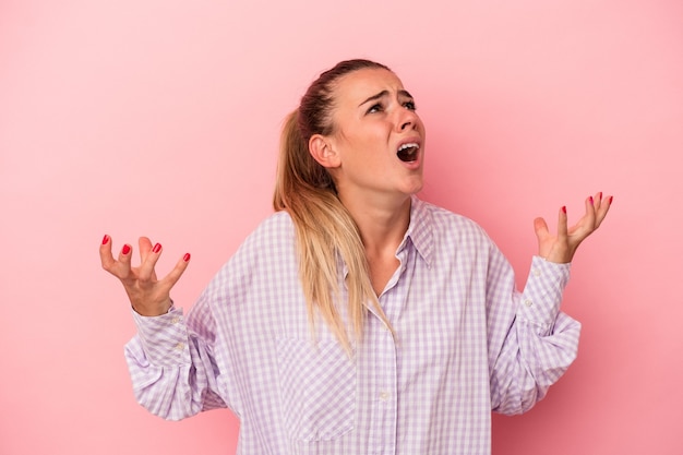 Young Russian woman isolated on pink background having fun covering half of face with palm.