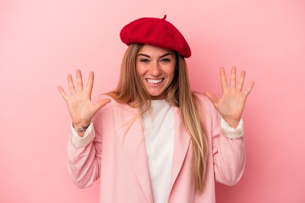 Young Russian woman isolated on pink background joyful and carefree showing a peace symbol with fingers.