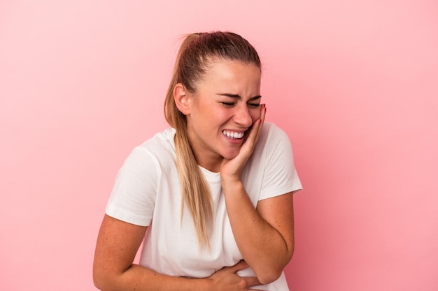 Young Russian woman isolated on pink background laughs happily and has fun keeping hands on stomach.