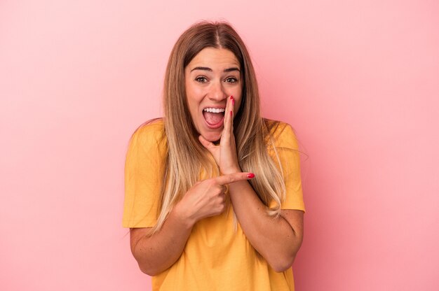 Young Russian woman isolated on pink background laughs joyfully keeping hands on head. Happiness concept.