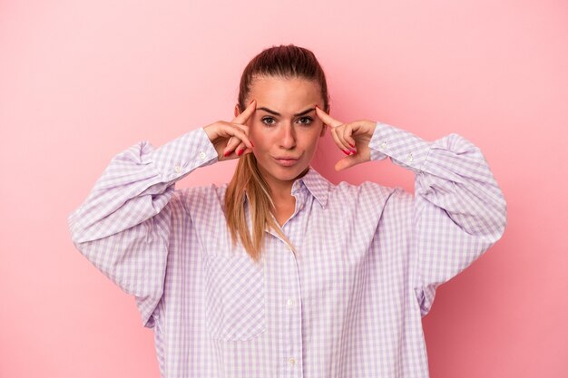 Young Russian woman isolated on pink background pointing upside with opened mouth.