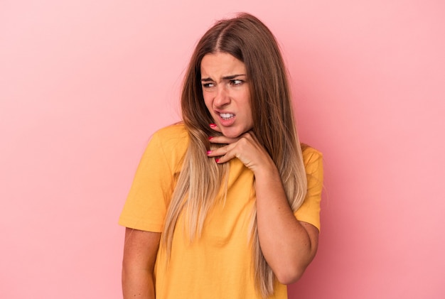 Giovane donna russa isolata su sfondo rosa che indica con l'indice uno spazio di copia, esprimendo eccitazione e desiderio.