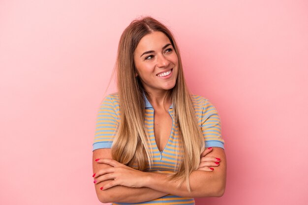 Young Russian woman isolated on pink background points with thumb finger away, laughing and carefree.