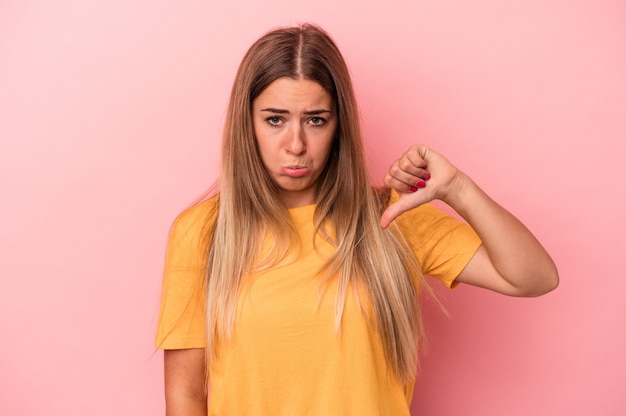 Young Russian woman isolated on pink background saying a gossip, pointing to side reporting something.