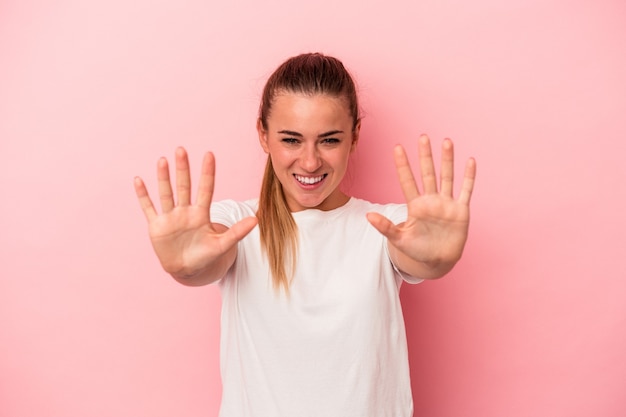 Young Russian woman isolated on pink background showing number ten with hands.