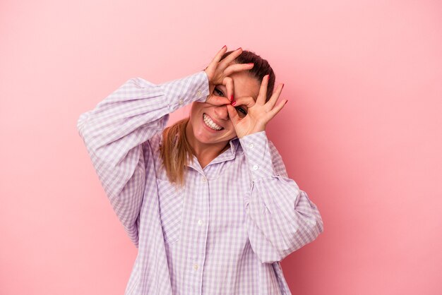 Young Russian woman isolated on pink background showing rock gesture with fingers