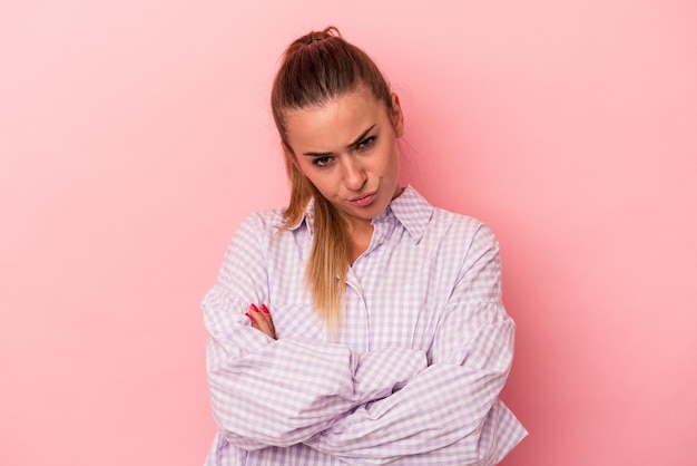 Young Russian woman isolated on pink background smiling and showing a heart shape with hands.