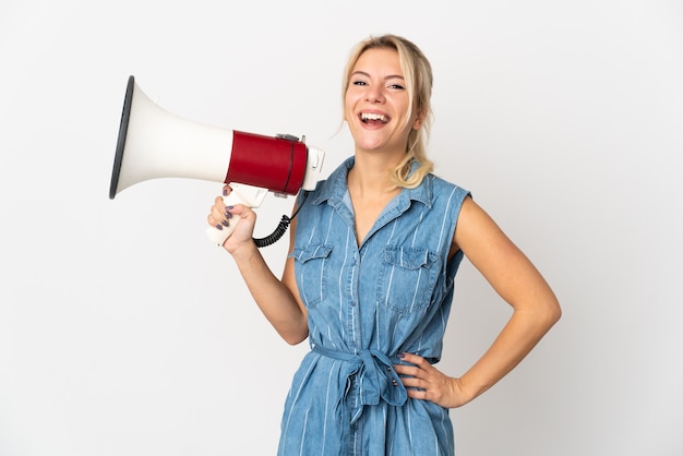 Young Russian woman isolated on white background holding a megaphone and smiling