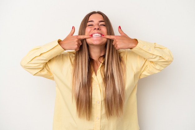 Young Russian woman isolated on white background smiles, pointing fingers at mouth.